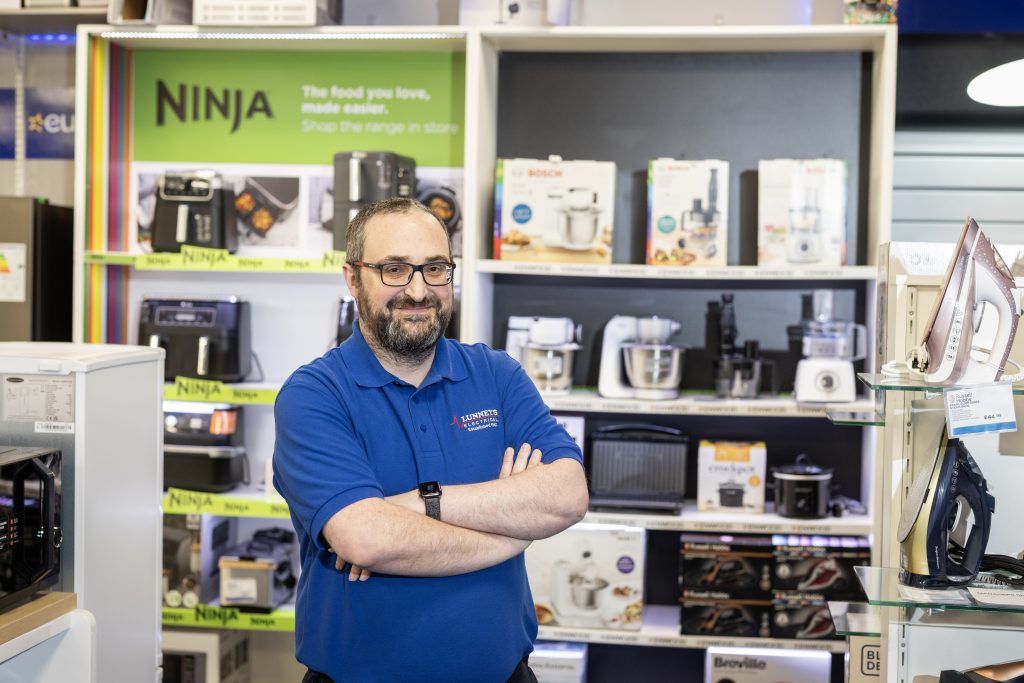 A man standing on a shop floor filled with home appliances like washing machines and fridges.