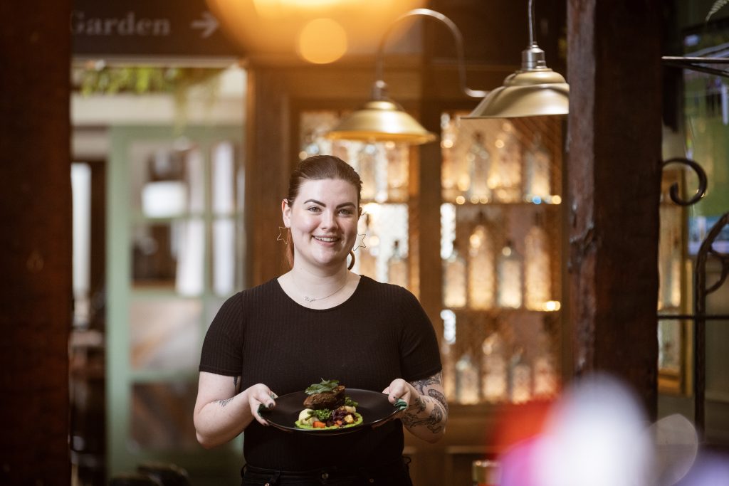 A woman dressed as a waitress carries food through a restaurant
